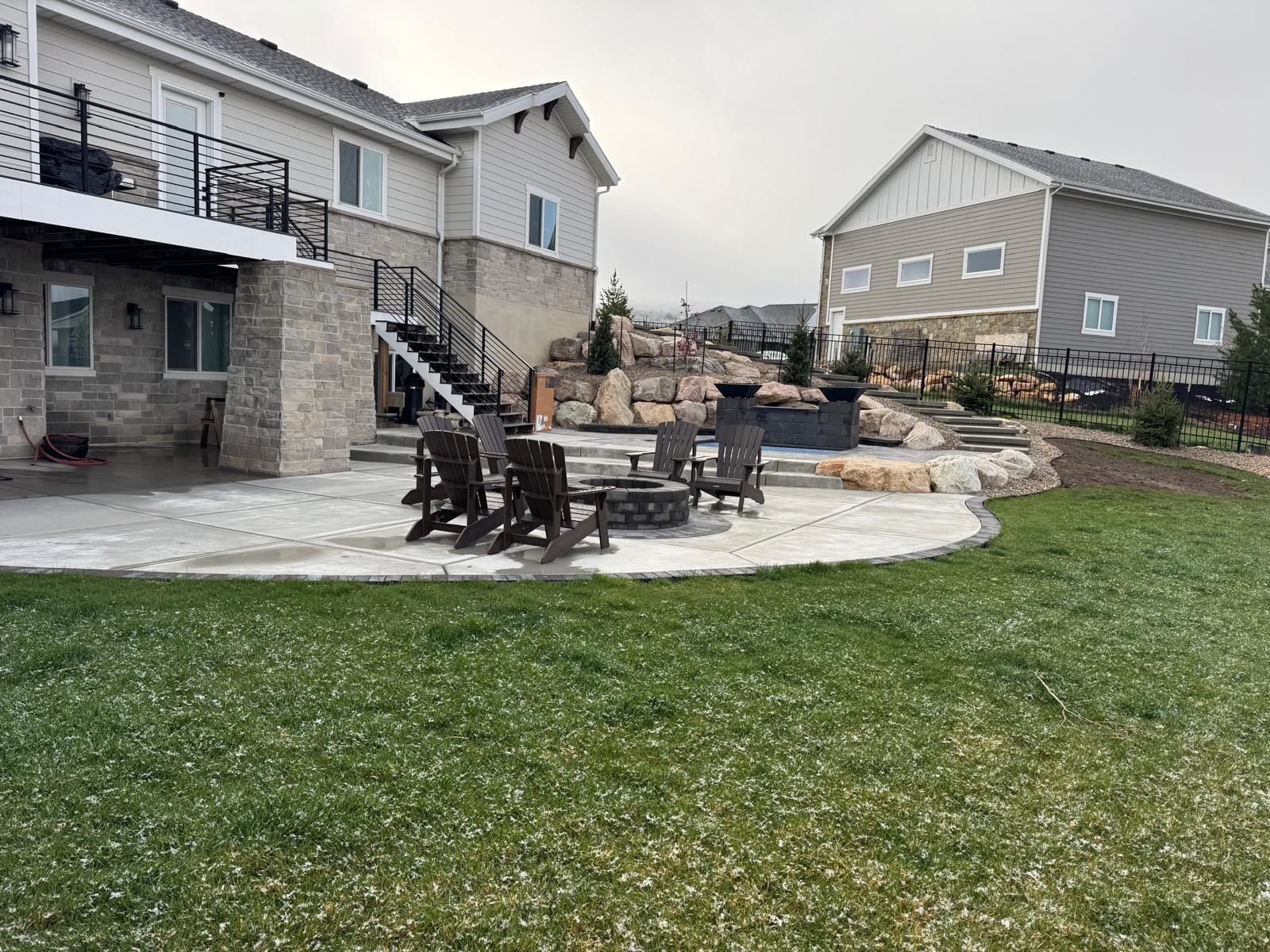 Low angle view of backyard paver patio fire pit with lush green lawn, Northern Utah