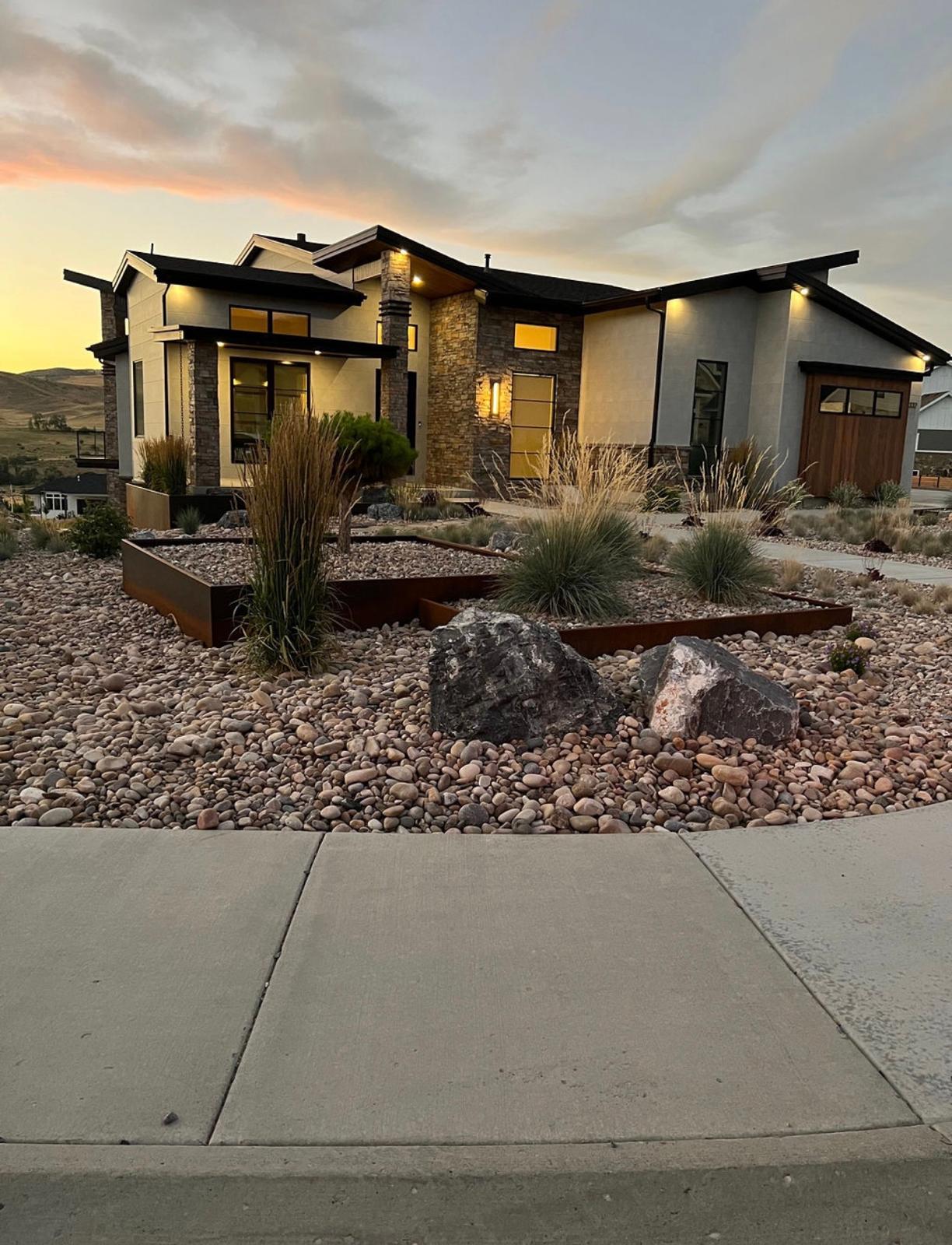 Modern home at dusk with professionally installed xeriscape front yard, drought-tolerant plants and decorative rock, Northern Utah