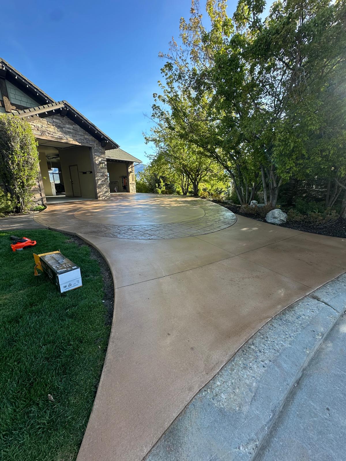 Wide stamped concrete driveway with manicured green lawn, Northern Utah residential home curb appeal